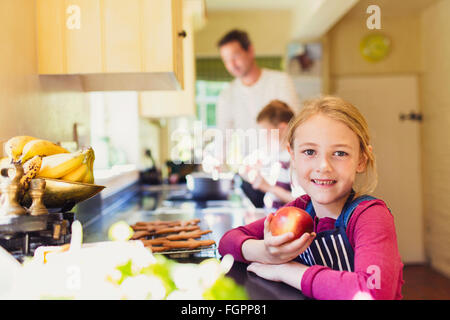 Portrait smiling girl eating apple in kitchen Stock Photo