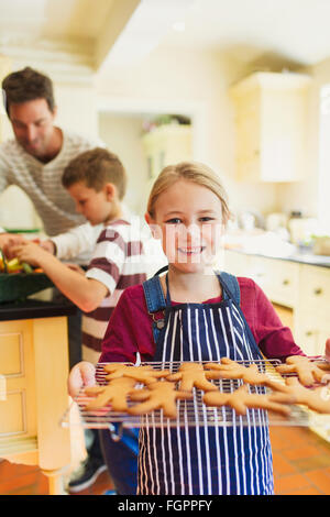 Portrait smiling girl holding rack of gingerbread cookies Stock Photo