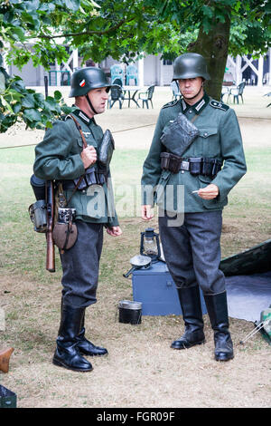 Second world war re-enactment. Two German Wehrmacht soldiers standing on sentry duty. One making eye-contact. Stock Photo