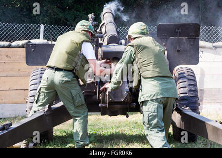 Vietnam war re-enactment. Rear view of two marines, both in flak jackets, reloading a US 105mm howitzer artillery gun seconds after it has fired. Stock Photo