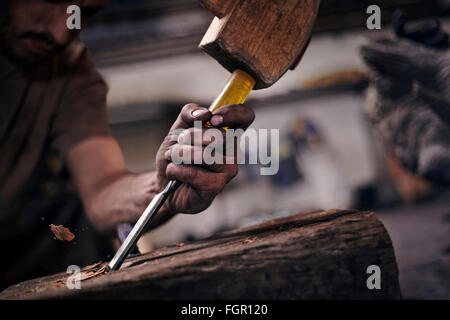 Close up of blacksmith chiseling wood with tool Stock Photo