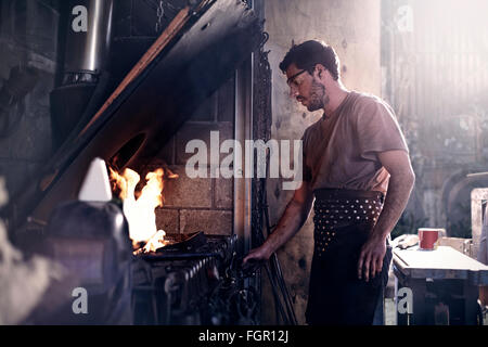 Blacksmith working at fire in forge Stock Photo