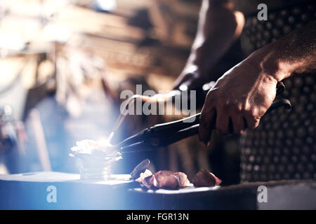 Close up of blacksmith heating metal with blowtorch in forge Stock Photo