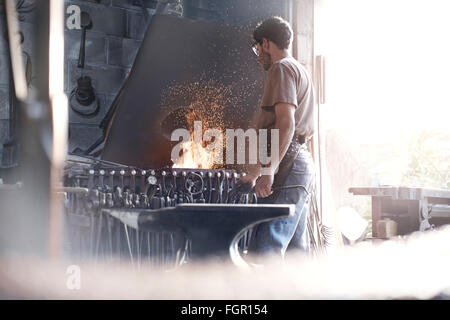 Blacksmith at fire in forge Stock Photo