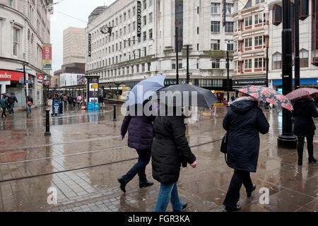 Manchester, UK - 17 February 2016: A group of women with umbrellas crossing Piccadilly Gardens, Manchester on a wet winter day Stock Photo