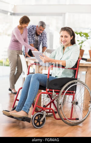 Casual businesswoman in wheelchair using tablet Stock Photo