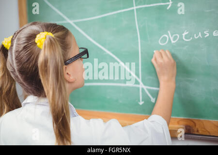 Pupil with lab coat writing on chalkboard in a classroom Stock Photo