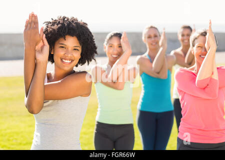 Smiling sporty women doing eagle pose in yoga class Stock Photo