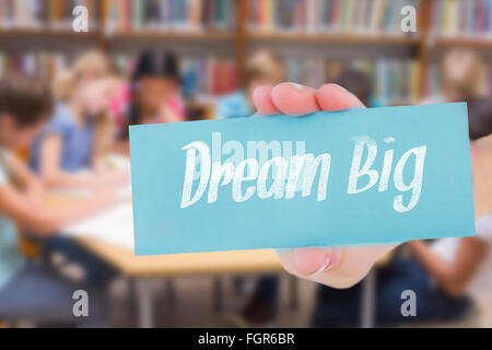 Dream big against cute pupils writing at desk in library Stock Photo