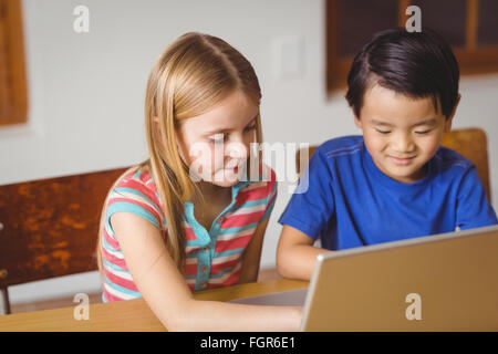 Cute pupils in class using laptop Stock Photo