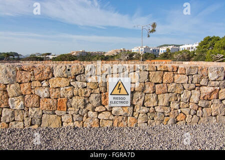 Drystone wall with warning sign for electricity in Spanish on December 16, 2015 in Ibiza, Balearic islands, Spain Stock Photo