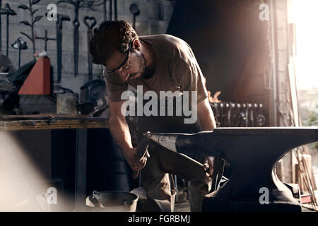 Blacksmith working at anvil in forge Stock Photo