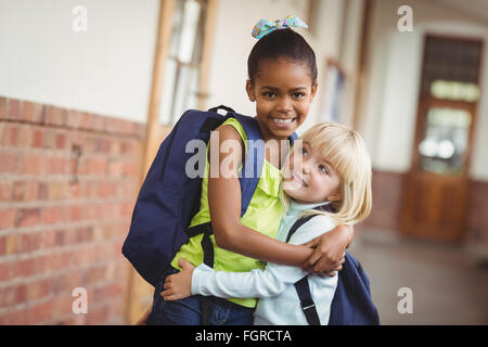 Cute pupils embracing at corridor Stock Photo