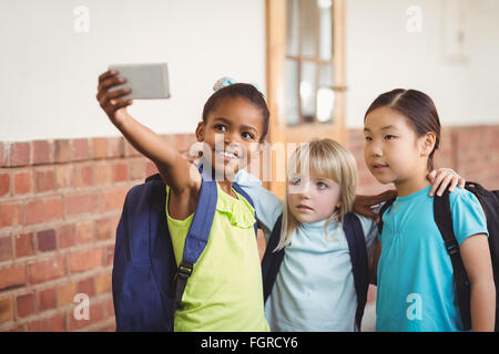 Cute pupils taking selfies at corridor Stock Photo