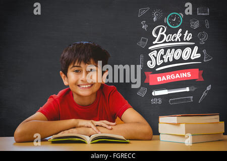 Composite image of cute boy reading book in library Stock Photo