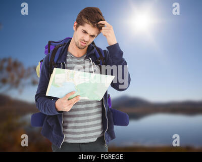 Composite image of man scratching head while looking in map Stock Photo