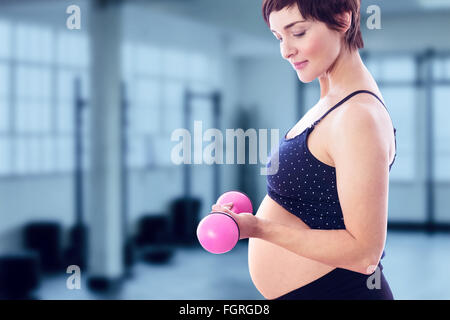 Composite image of happy pregnant woman lifting dumbbell Stock Photo