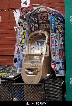 A graffiti and sticker covered ATM on Ludlow Street off Stanton on the Lower East Side of Manhattan, New York City. Stock Photo