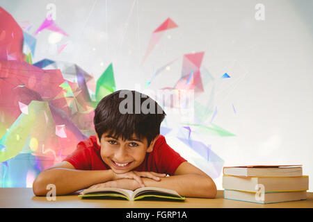 Composite image of portrait of boy reading book in library Stock Photo