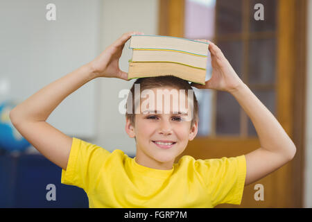 Cute pupil balancing books on head in a classroom Stock Photo - Alamy