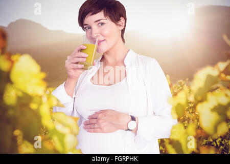 Composite image of portrait of happy pregnant woman drinking orange juice Stock Photo