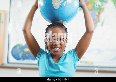 Smiling pupil holding globe in front of world map Stock Photo - Alamy