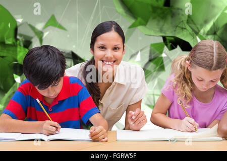 Composite image of pretty teacher helping pupils in library Stock Photo