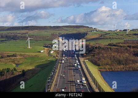 heavy traffic travelling on the m62 passing windmills near moss moor huddersfield yorkshire uk Stock Photo