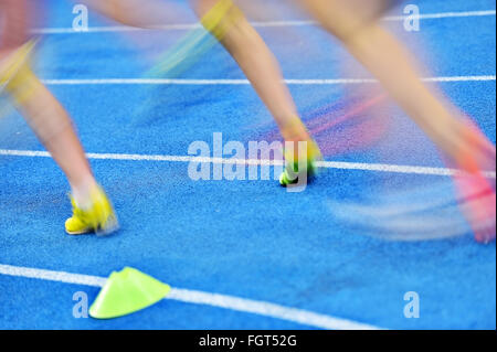 Blurred athletes by a slow camera shutter speed are competing on blue sprint track Stock Photo