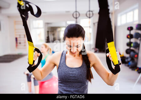Woman in gym training arms with trx fitness strips Stock Photo