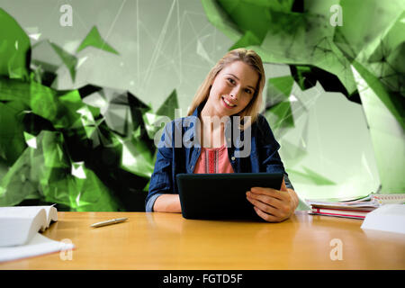 Composite image of student studying in the library with tablet Stock Photo