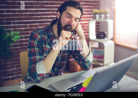 Creative Businessman yawning with hand on chin Stock Photo