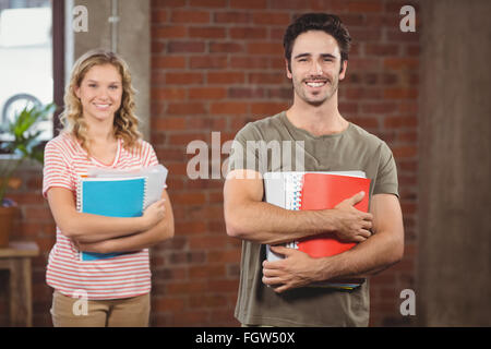 Portrait of smiling businessman holding files and folders in office Stock Photo