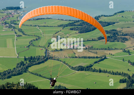 Fuessen, Germany - September 11, 2010: orange Paraglider fly over the Foggenlake Stock Photo