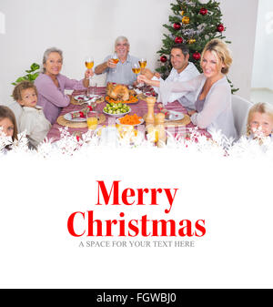 Composite image of family raising their glasses at christmas Stock Photo