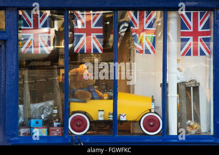 Teddy bear in a tin car in a burford shop window. Cotswolds, Oxfordshire, England Stock Photo