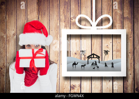 Composite image of brunette in red gloves and santa hat showing gift Stock Photo