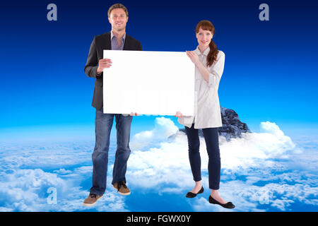Composite image of smiling couple holding large sign Stock Photo