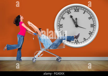 Composite image of young couple having fun with shopping cart Stock Photo