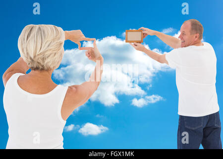 Composite image of mature couple hanging up picture frame Stock Photo