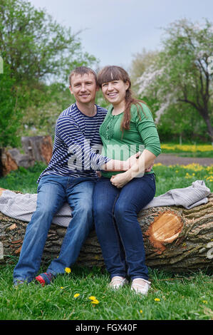 husband and his pregnant wife sitting on a wooden deck Stock Photo