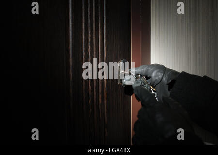 man's hand in a glove key opens the door Stock Photo