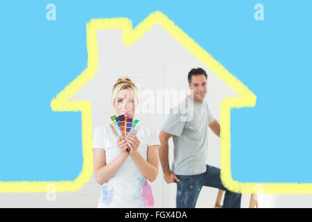 Composite image of couple with color swatches and ladder in a new house Stock Photo