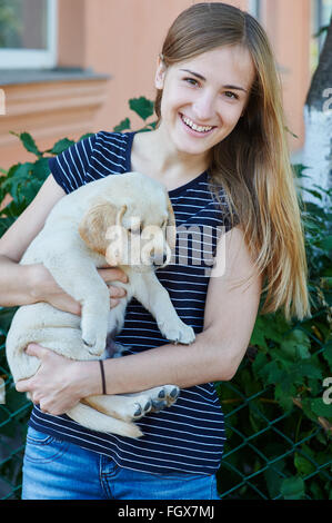 beautiful blonde woman holds a white puppy Stock Photo