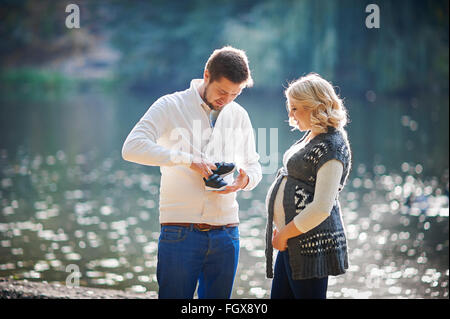 Happy pregnant women and her husband during the walk with a man near the lake Stock Photo