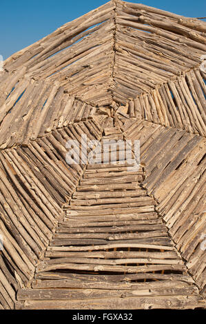 Big wicker wooden parasol against blue sky on beach Stock Photo