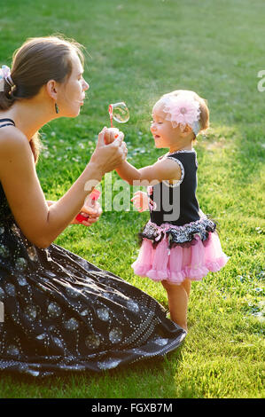 young mother and her little daughter playing on grass Stock Photo
