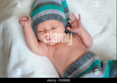 little baby boy in a knitted hat lying on the bed Stock Photo