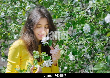 Beautiful woman smelling a flower in the spring garden Stock Photo