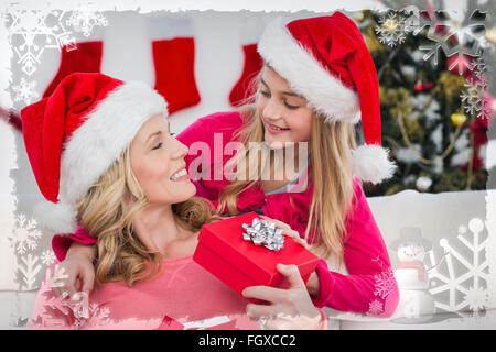 Composite image of festive mother and daughter with gift Stock Photo